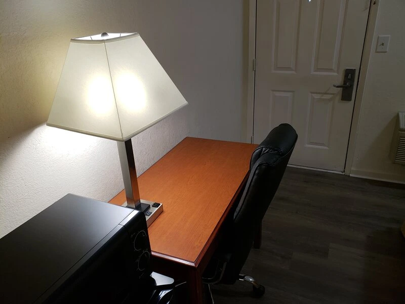 Wooden desk with lamp and black leather office chair near door