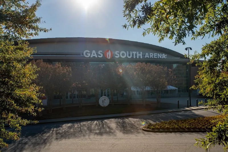 Gas South Arena exterior with curved roof, trees, and sun flare